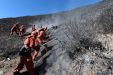 Firemen Put Out The Smouldering Remains Of A Fire On A Mountain