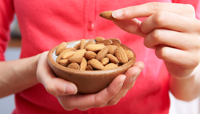 49871539 Woman Eating Healthy Snack Of Almonds