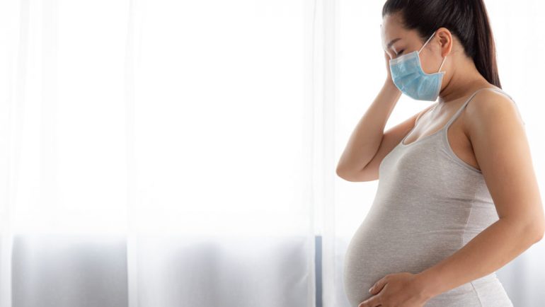 Pregnant Woman Wearing Pollution Mask At Home